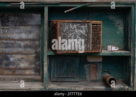 Rusty, old air conditioner unit on broken down, teal shelf. Stock Photo