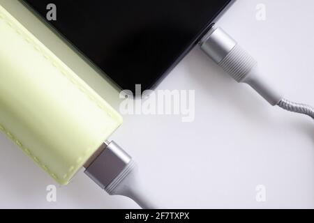 Mobile phone is connected with cable to power bank closeup Stock Photo