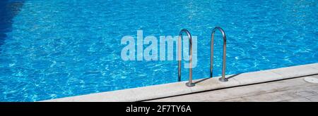 Close up grab bars ladder in the blue swimming pool outdoors Stock Photo