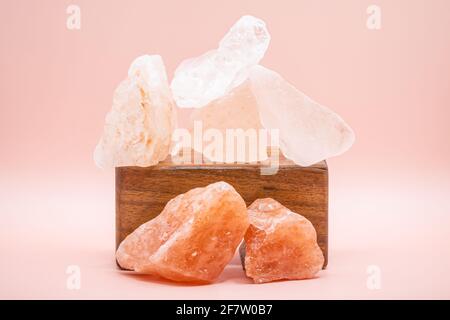Large chunks of Himalayan sea salt are stacked on top of each other for peace and balance. Supported by a wooden stand and isolated against a soft pin Stock Photo