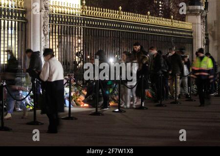 Rip prince Philip everyone was saying outside Buckingham Palace until late last night. There was a lot of people there leaving  flowers at the gates and someone left a teddy bear also.a lot of police as well and they arrested a guy for shouting and being drank .another guy was holding to candles and was trying to get a selfie of himself as well. Some people were crying and a lot of people were walking around the palace. here was a lot of traffic as well .usually you do not get that much traffic outside the palace at this time of the day.the flag was a half mast Stock Photo