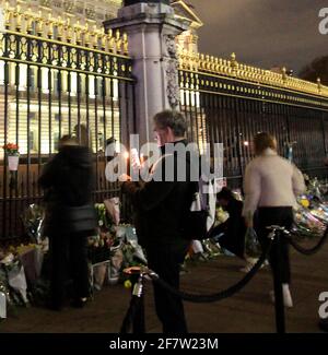 Rip prince Philip everyone was saying outside Buckingham Palace until late last night. There was a lot of people there leaving  flowers at the gates and someone left a teddy bear also.a lot of police as well and they arrested a guy for shouting and being drank .another guy was holding to candles and was trying to get a selfie of himself as well. Some people were crying and a lot of people were walking around the palace. here was a lot of traffic as well .usually you do not get that much traffic outside the palace at this time of the day.the flag was a half mast Stock Photo