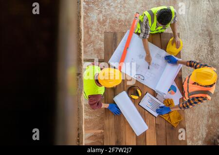 Top view of Team work construction engineer and architects working meeting discussing designing planing measuring layout of building blueprints in con Stock Photo