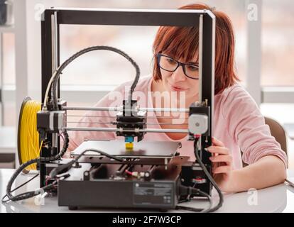 Beautiful woman wearing glasses working with 3D printer on project Stock Photo