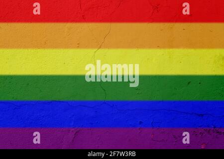 Rainbow colored LGBT pride flag painted on a cracked concrete wall. High resolution full frame textured background of a colorful concrete wall. Stock Photo