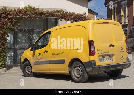 Carcassonne Aude France 04.09.21 Bright small yellow french postal delivery van parked in front of a building with vines growing around the doors. Stock Photo