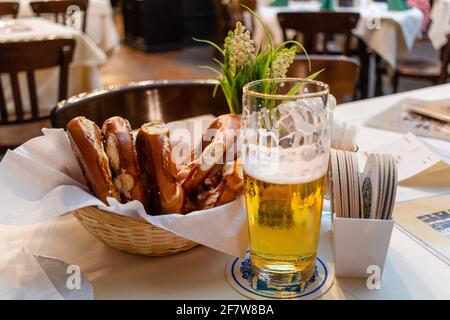 Close up Appetizing German Recipe with Sausage. Classic German dinner of fried sausages with braised cabbage on large white plates with light beer, st Stock Photo