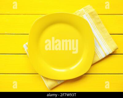 Empty yellow plate, napkin in white and yellow pattern on wooden background Stock Photo