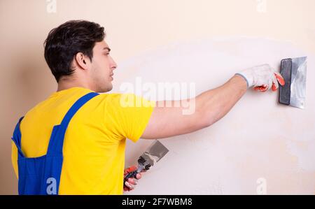 The young contractor employee applying plaster on wall Stock Photo