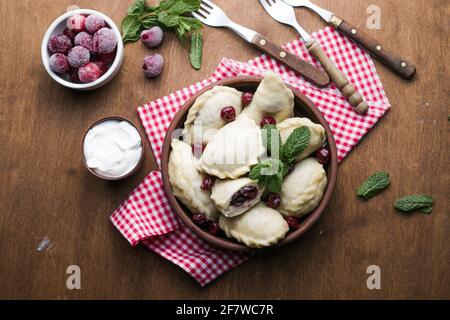 Pierogi with cherries. Vareniki dumplings. Traditional Ukrainian food. Cooked and served with sour cream and berry Stock Photo