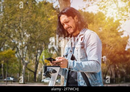 Happy young handsome hispanic man using smartphone at the park Stock Photo