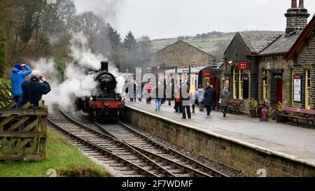People (enthusiasts & fans) on platform & historic steam train loco LMS class 2 46521 puffing smoke clouds - Oxenhope Station, KWV Railway, England UK Stock Photo