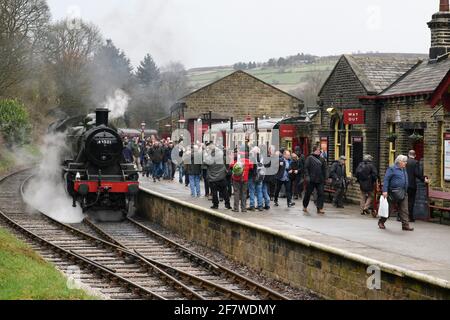 People (enthusiasts & fans) on platform & historic steam train loco LMS class 2 46521 puffing smoke clouds - Oxenhope Station, KWV Railway, England UK Stock Photo