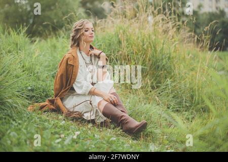 Perfect woman in boho style dress sitting on grass Stock Photo