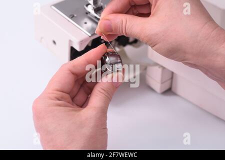 seamstress inserts bobbin with a thread in sewing-machine. close-up. Stock Photo