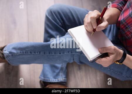 Man sitting on floor thinking with notebook and pen. Student or designer creative concept Stock Photo