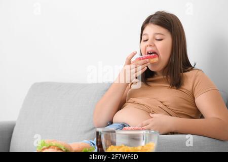 Overweight girl eating unhealthy food at home Stock Photo