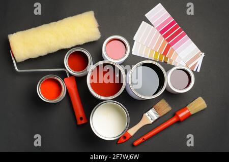Cans of paints, palette samples, roller and brushes on dark background Stock Photo