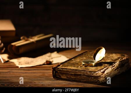Old book with compass on table against dark background, closeup Stock Photo