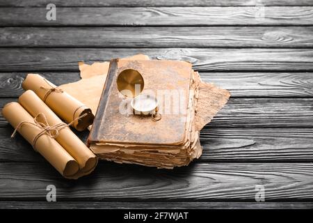 Old book with compass and scrolls on dark wooden background Stock Photo