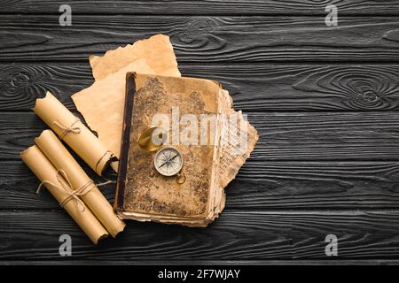 Old book with compass and scrolls on dark wooden background Stock Photo