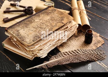 Old book, feather, compass, scrolls and keys on dark wooden background Stock Photo