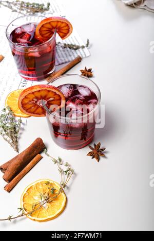 Cold mulled wine with cherry and bloody orange. Alcoholic beverage still life. Sicilian oranges, cinnamon sticks, oregano, anise and dried ginger. Lig