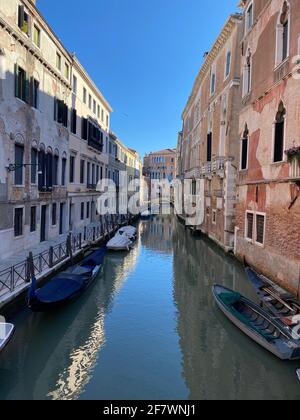 Small boat on a canal street in Venice with beautiful colorful houses ...