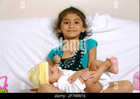 Playful and pretty Indian asian little sisters or friends in playful mood hugging kissing each other Isolated over white background Stock Photo