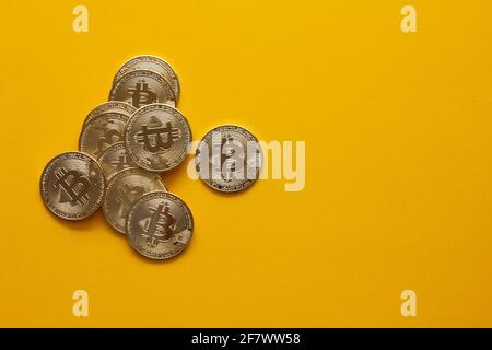 Overhead view of some of bitcoins on a yellow background and copy space. Golden BTC coins, Stock Market of cryptocurrencies and decentralized finances Stock Photo