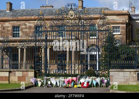 Hillsborough Castle, Hillsborough, County Down, Northern Ireland, UK. 10 April 2021. With the Union flag at half-mast, floral tributes have been left outside the gates of HM The Queen's official residence in Northern Ireland as the public mourn the loss of Prince Philip, Duke of Edinburgh, who died yesterday. Credit: David Hunter/Alamy Live News.