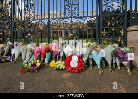 Hillsborough Castle, Hillsborough, County Down, Northern Ireland, UK. 10 April 2021. With the Union flag at half-mast, floral tributes have been left outside the gates of HM The Queen's official residence in Northern Ireland as the public mourn the loss of Prince Philip, Duke of Edinburgh, who died yesterday. Credit: David Hunter/Alamy Live News.