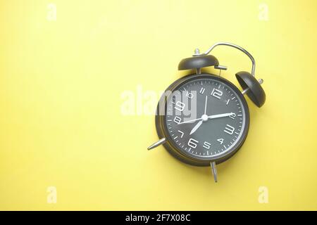 black color old alarm clock on yellow background. Stock Photo