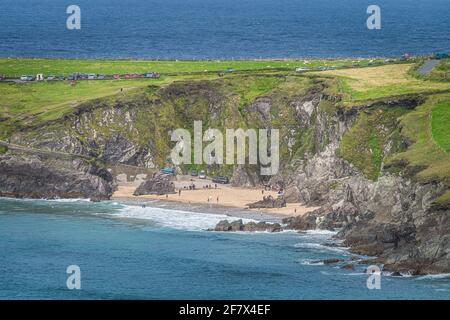 Tourist swimming in the see and relaxing on small hidden Coumeenoole Beach between cliffs in Dingle Peninsula, Wild Atlantic Way, Kerry, Ireland Stock Photo