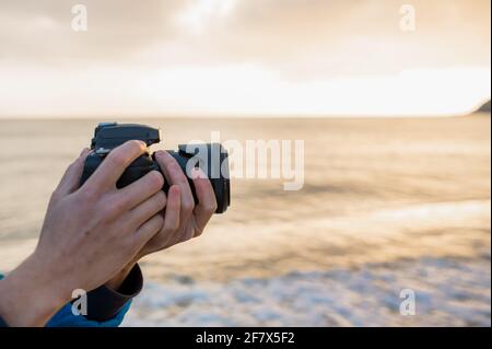 Side view unrecognizable photographer holding reflex camera taking a photo in natural landscape. Stock Photo
