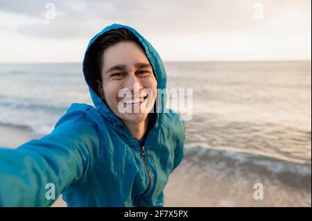 Young happy male doing a selfie on the beach in Sardinia during sunset light. Stock Photo