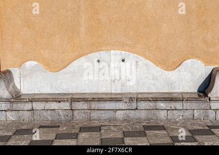 Ancient stone seat on a checkerboard floor Stock Photo