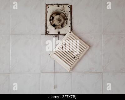 Dirty ventilation air grille with fan at home close up on white wall. Dust condition technology, dangerous old house air circulation system. Bad Stock Photo