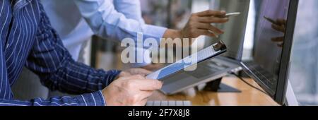 broker showing some ascending to his colleague planning and analyzing graph stock market trading with stock chart data on multiple computer screens Stock Photo