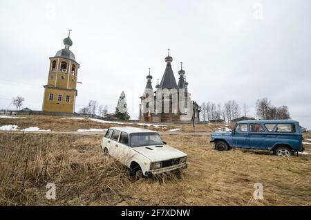 April, 2021 - Nyonoksa. Old Russian rusty cars on the background of wooden Orthodox churches. Russia, Arkhangelsk region Stock Photo