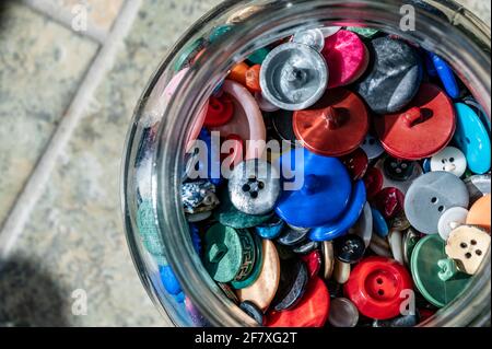 various types of buttons stored in a glass container Stock Photo