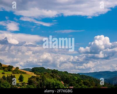 Cumulus congestus or towering cumulus - forming in the blue sky over hilly landscape Stock Photo
