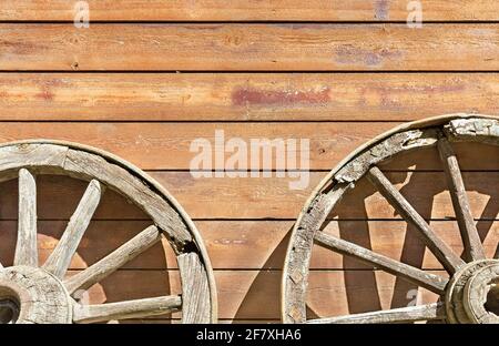 old wheels from a cart on a background of a wooden wall Stock Photo