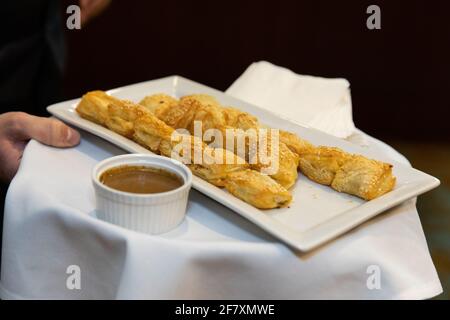 small appetizers for guests in a square white plate being held by a server at a party Stock Photo