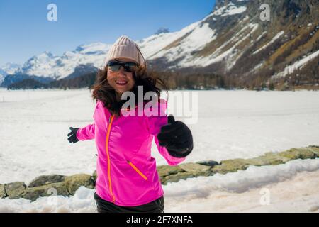 young Chinese woman enjoying amazing snowy landscape view - happy and beautiful Asian girl playful in front of frozen lake and snow mountains during S Stock Photo