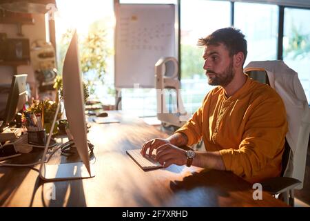 A young male office worker is focused on the job at the desk in a working atmosphere in the office. Business, office, job Stock Photo