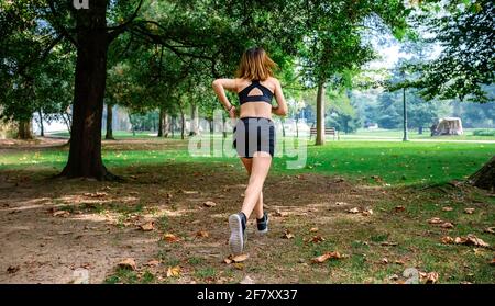 Female athlete running through a park Stock Photo