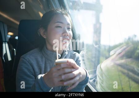 train travel getaway - lifestyle portrait of young happy and beautiful Asian Chinese woman traveling on railway looking through window  drinking coffe Stock Photo