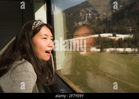 train travel getaway - lifestyle portrait of young happy and beautiful Asian Japanese woman traveling on railway looking through window relaxed and ch Stock Photo