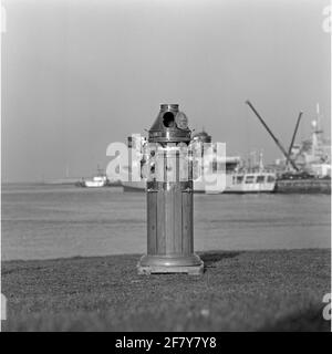 Boiler house for the magnetic compass of the Marine Barracks Willemsoord, placed on the lawn on the port basin side. In the background a standard frequency of the Kortenaerklass. Stock Photo